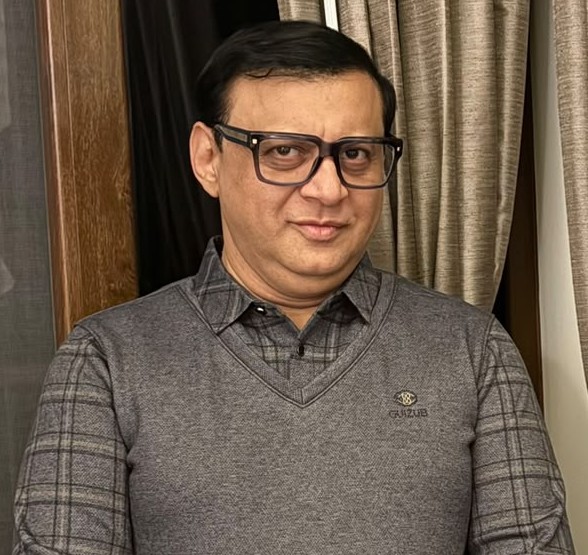 Portrait of Deepak Thimaya in a grey sweater and glasses